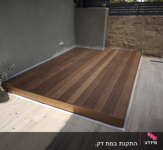 דק עץ מותקן בחצר עם כלים מסביב